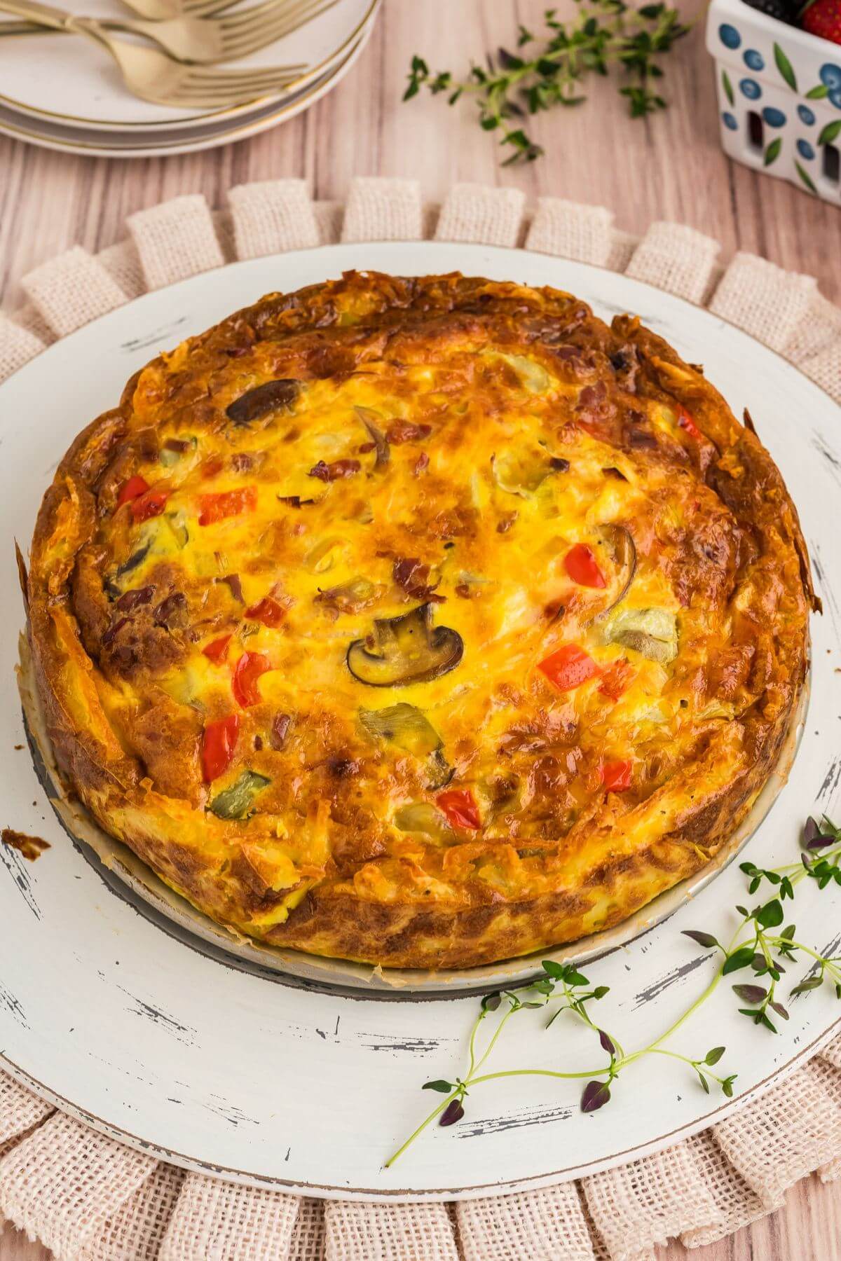 Hash brown crust quiche on tray with fresh herbs. 