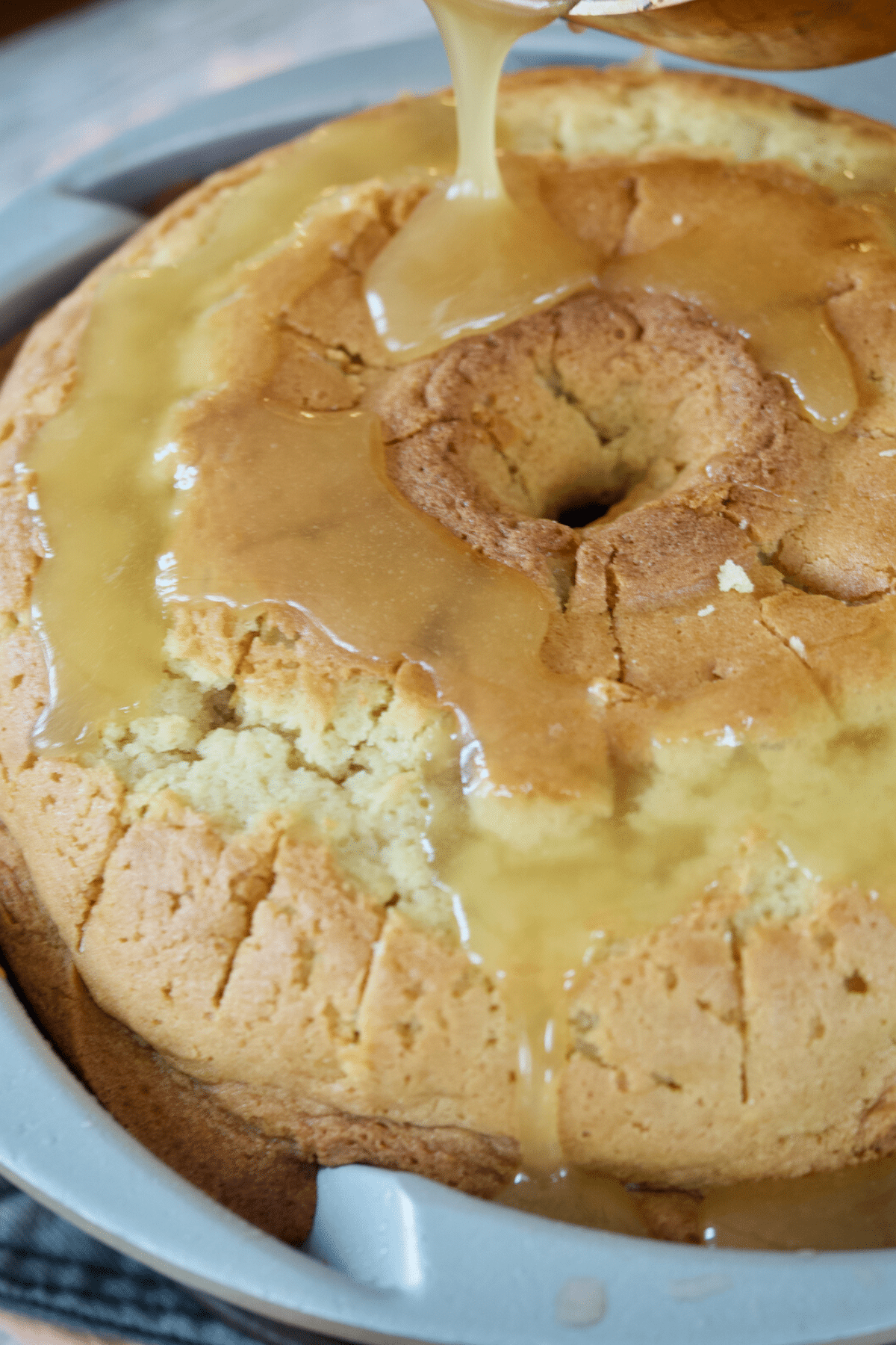 Pouring vanilla sauce over the warm cake.