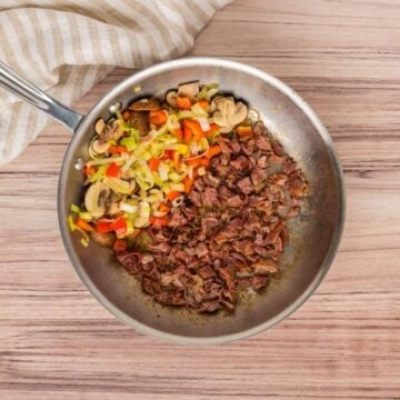 Sauteing vegetables and prosciutto in pan.