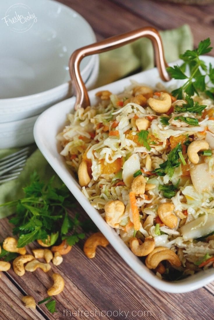 Ramen Noodle salad with cabbage and cashews in square salad bowl. 