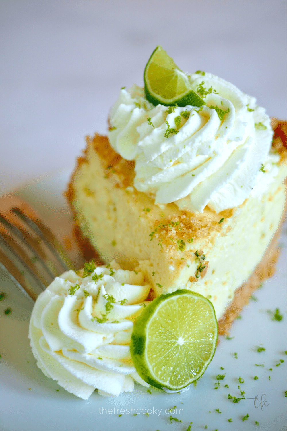 Best Key Lime Pie with slice decorated with a swirl of whipped cream and wedges of lime.