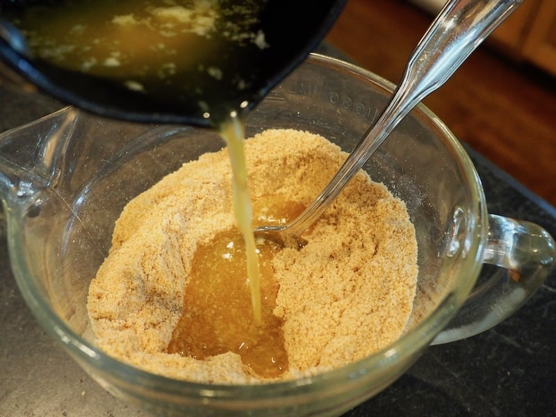 Pouring butter into graham cracker crumbs for Key Lime Pie.