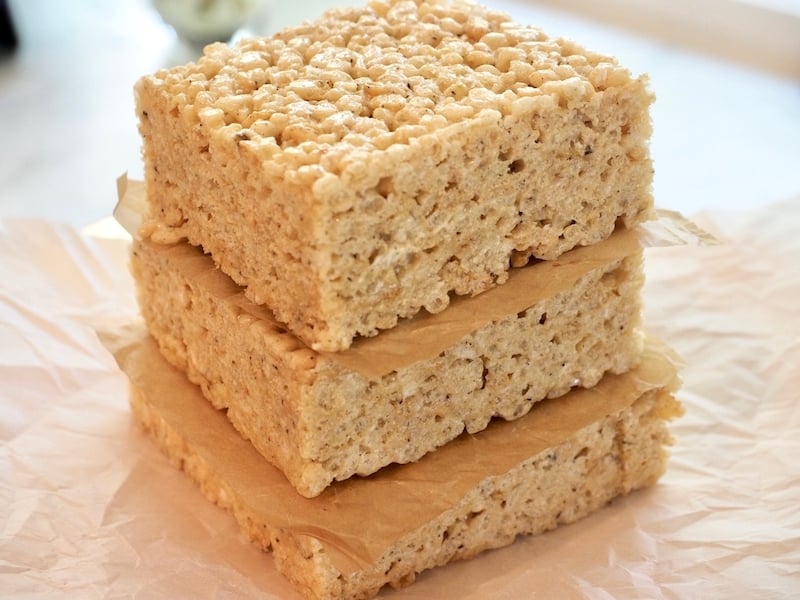  Stack of three gigantic squares of rice crispie treats with parchment paper between them. 