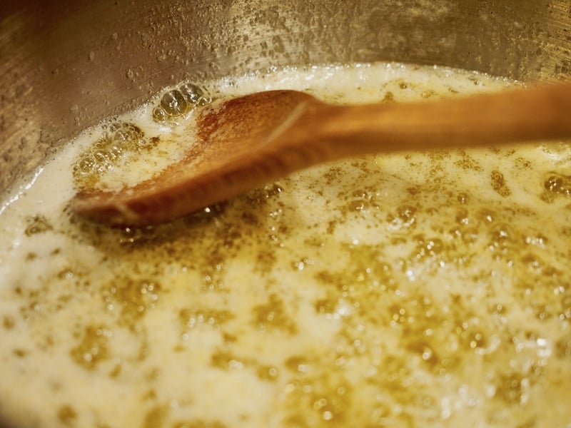 a wooden spoon in melting, simmering bubbling butter