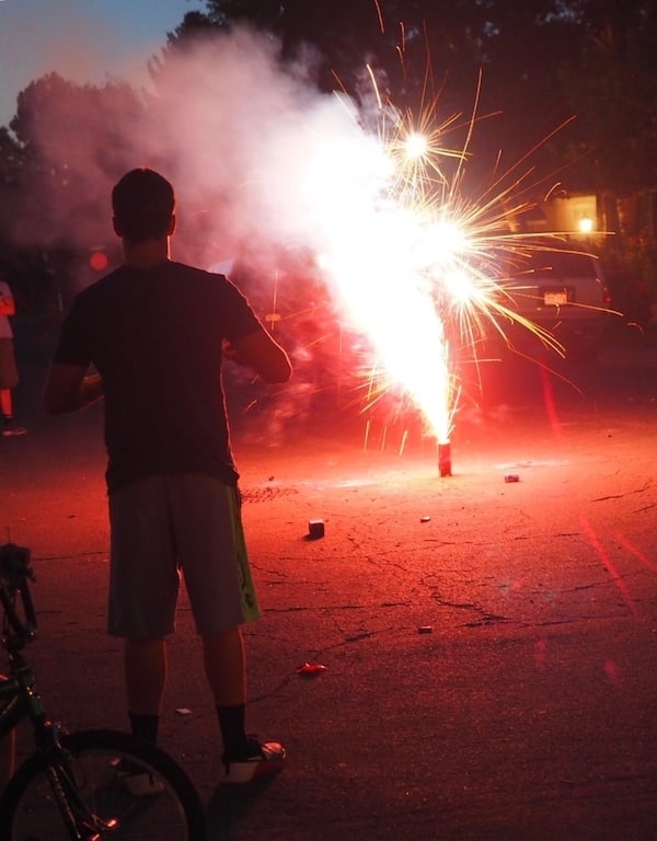 Teenage Boy standing in front of a fountain firework on the 4th of July.