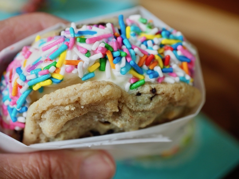 Cool and creamy ice cream, sandwiched between two chewy Chocolate Chip Cookies, dipped in sprinkles no less -- the very essence of summertime! #thefreshcooky #icecreamsandwich #chocolatechipcookies #icecream #dessert