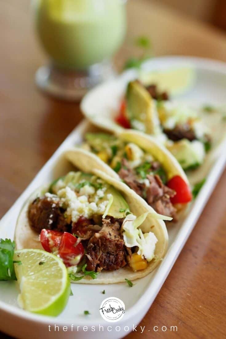 Pinterest image with plate of barbacoa beef street tacos with lime, avocado and cilantro.