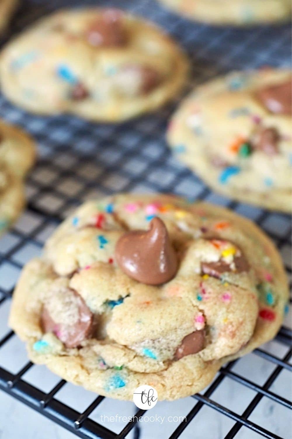 Image of Cake Batter Chocolate Chip Cookies on black wire cooling rack with soft chocolate chips.