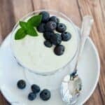 Homemade Greek yogurt in glass cup with blueberries and mint.