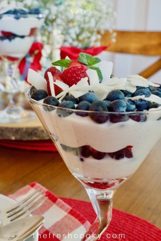 Martini glass filled with layers of red white and blue using yogurt, berries. 