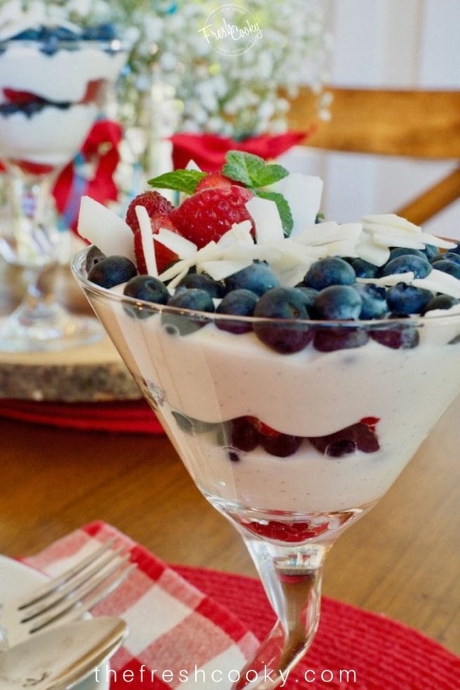 Martini glass filled with layers of red white and blue using yogurt, berries.