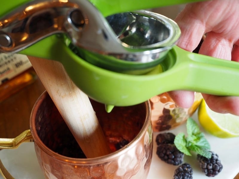 Squeezing Lime into a copper mug for a blackberry cocktail.