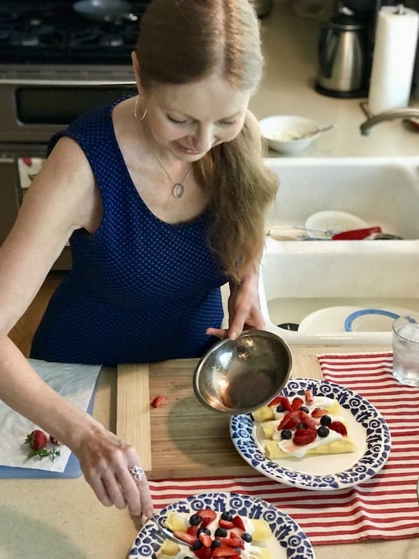 my friend Eliza, preparing crepes with creme and fresh berries near her kitchen sink.