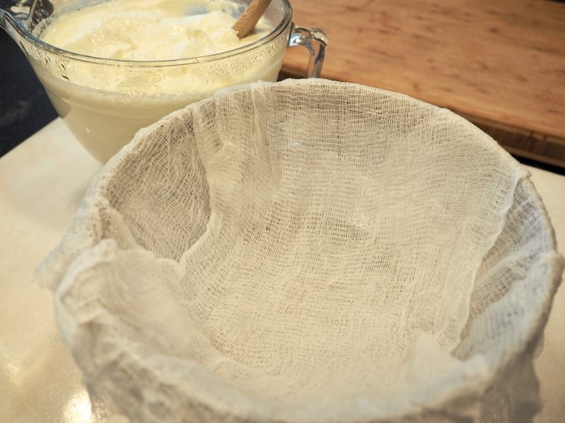 strainer lined with cheesecloth with yogurt behind in mixing bowl. thefreshcooky.com