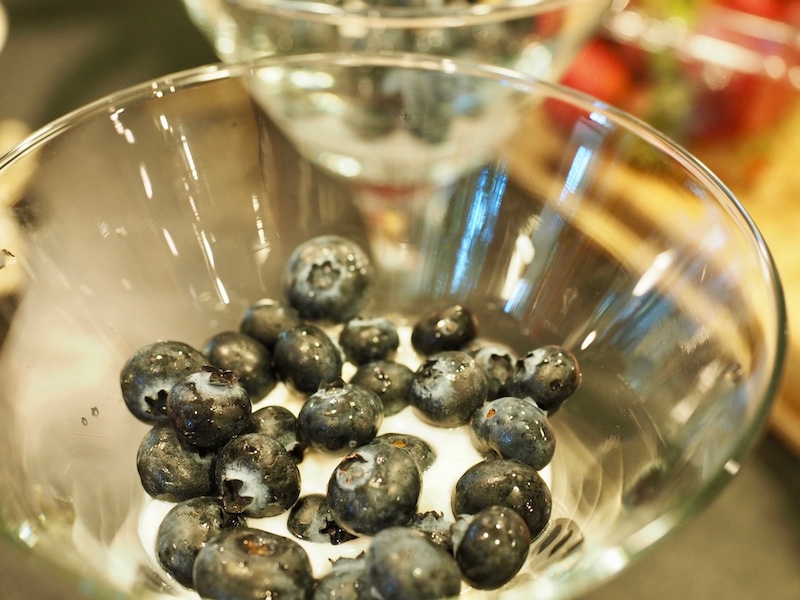 A layer of blueberries on top of vanilla yogurt, for a layered red, white and blue yogurt parfait. 