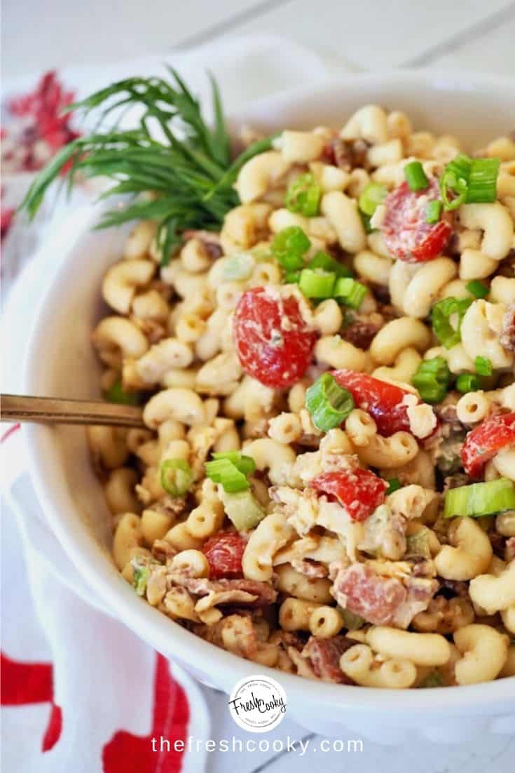 Bowl of creamy balsamic ranch bacon macaroni salad with fresh tarragon on side.