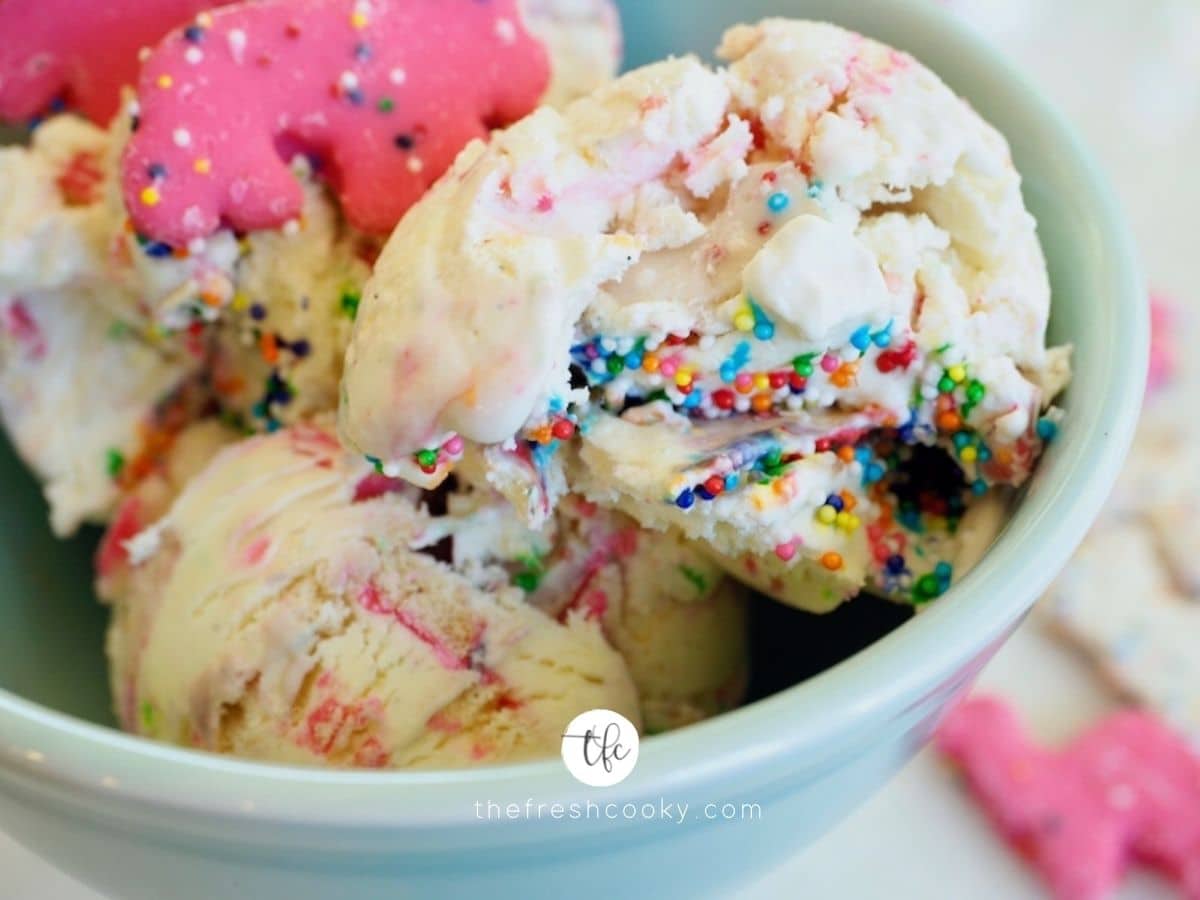 Circus Animal cookie ice cream close up shot with pink and white animal frosted cookies in a bowl with sprinkles on top. 