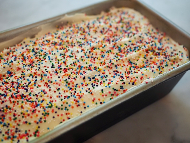 Circus Animal Ice Cream in loaf pan ready for freezer, top sprinkled with non-pariels in rainbow colors.