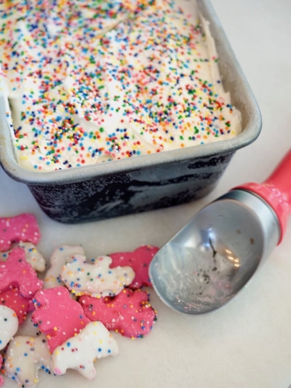 No churn circus animal ice cream with sprinkles on top, circus animal pink and white cookies and a pink handled ice cream scoop