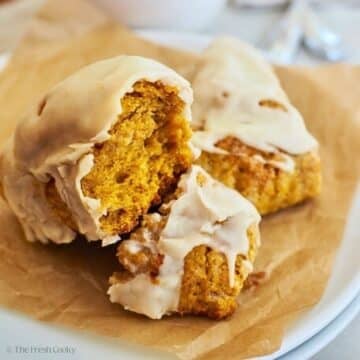 Pumpkin scones with a maple brown butter glaze on a plate.