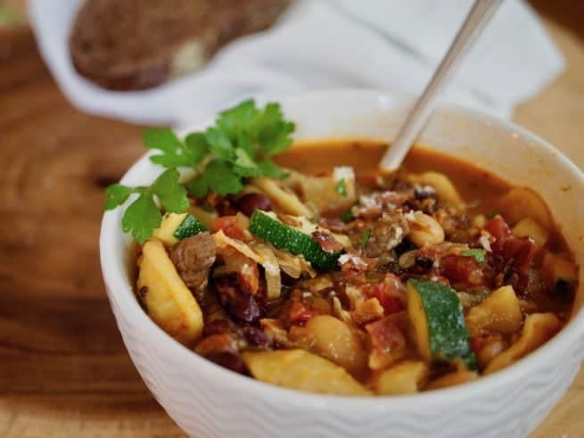 bowl of bacon beef minestrone soup with spoon 