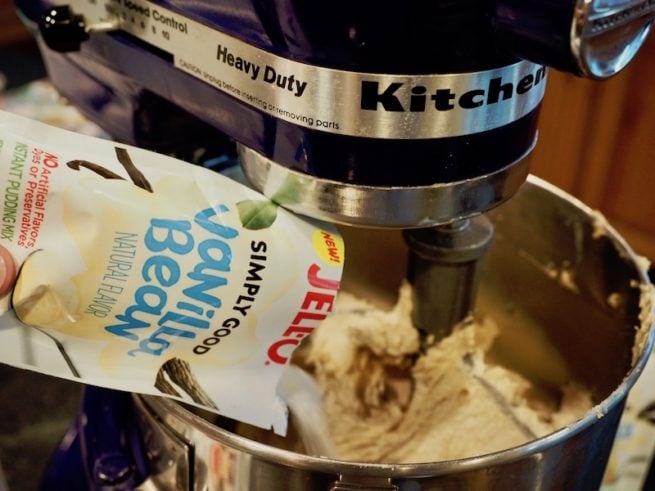 Pouring pudding mix into triple chocolate chip cookie batter. 