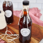 Square image of two bottles of homemade vanilla extract with pretty labels.