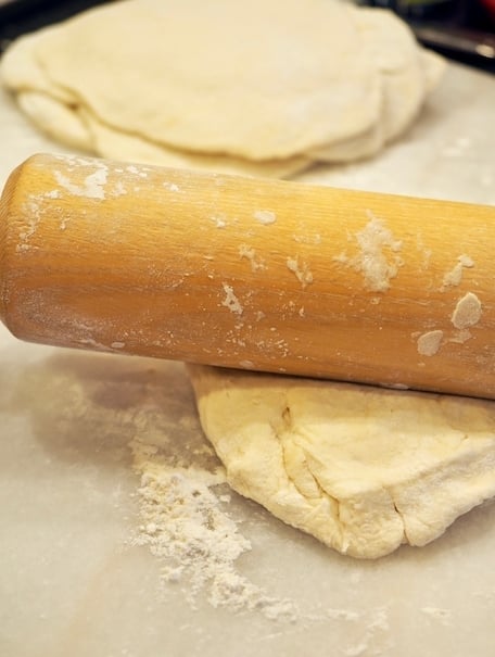 Rolling out pieces of naan dough into flatbread. 