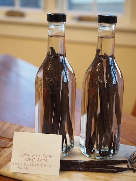 Two glass bottles with 8-10 vanilla beans in them filled with vodka on made date, which states 11-29-17.