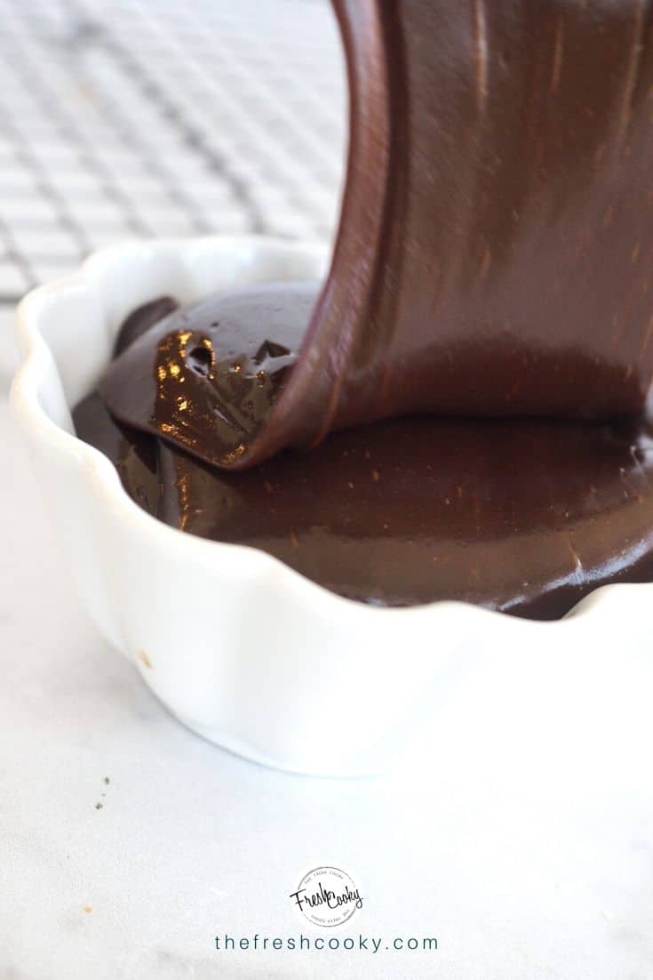 Stream of chocolate ganache being poured into a white bowl. 