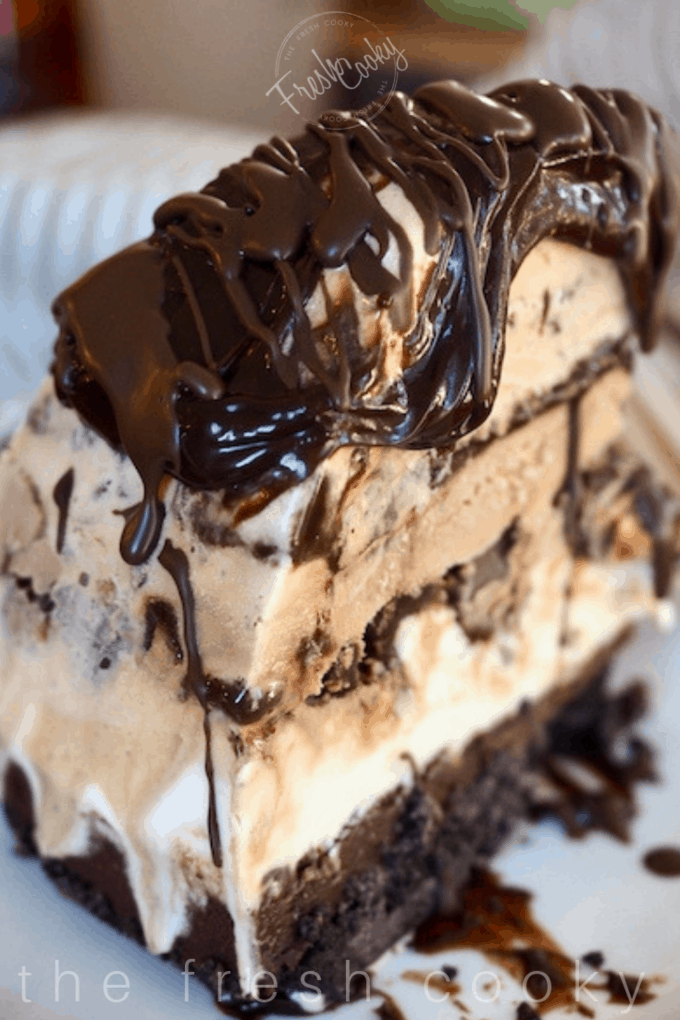 Slice of mile high mud pie on plate with extra hot fudge. 