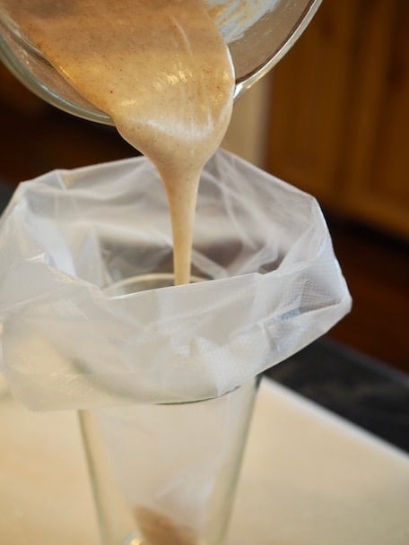 Pouring Browned Butter Glaze into a piping bag, sitting with top folded down in a tall glass. thefreshcooky.com 