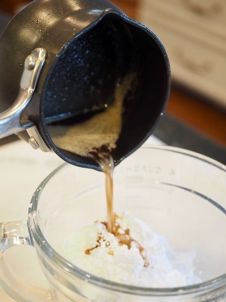 Pouring browned butter from butter melter, into a mixing bowl with powdered sugar. | www.thefreshcooky.com