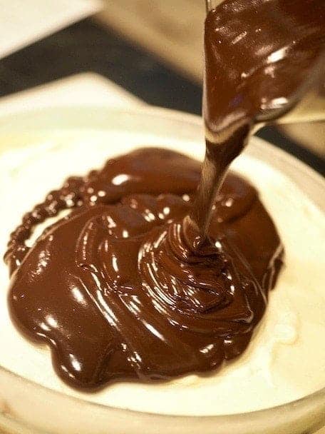 Pouring chocolate ganache on top of the vanilla layer for ice cream cake. 