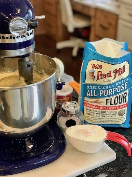 Adding all purpose flour to cookie batter, salt, mixer, baking powder in cup. 