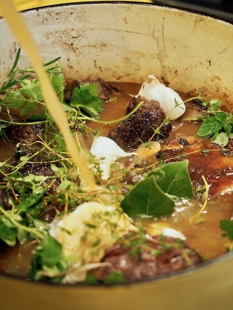 Pouring in beef broth into Dutch Oven for Italian Short Ribs.