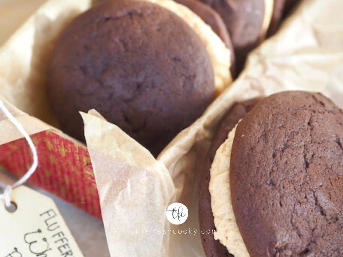 Facebook image of fluffernutter whoopie pies in red container with parchment paper and one leaning against the container.