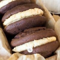 Facebook image with three whoopie pies with fluffernutter frosting stacked in a pan with parchment paper.