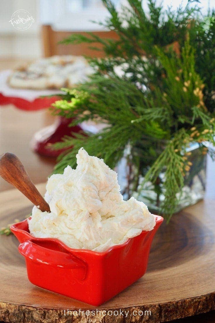 red bowl with heaps of vanilla buttercream frosting and a spreader with sugar cookies in background |thefreshcooky