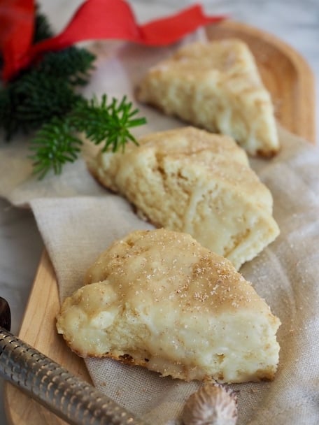 2 Eggnog Scones with White Chocolate Glaze, some pine greens, red ribbon and nutmeg grater in foreground. | www.thefreshcooky.com