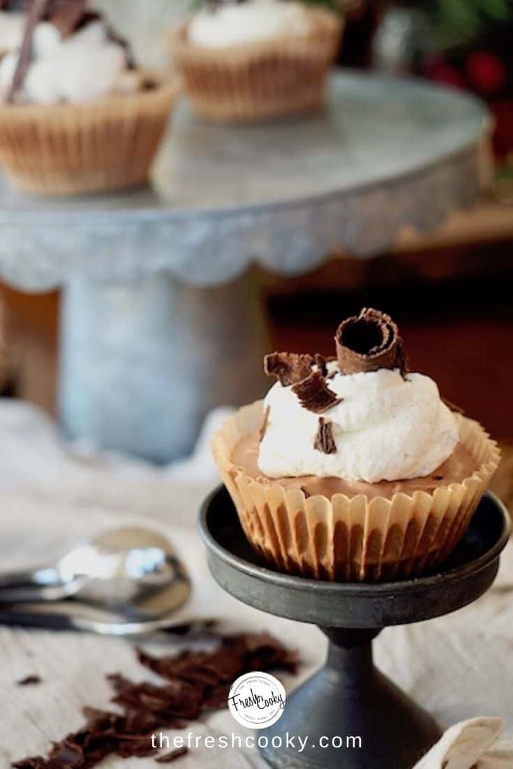 mini chocolate french silk pies, in a cupcake wrapper on a metallic stand, with a dollop of whipped cream and chocolate shavings. thefreshcooky.com 