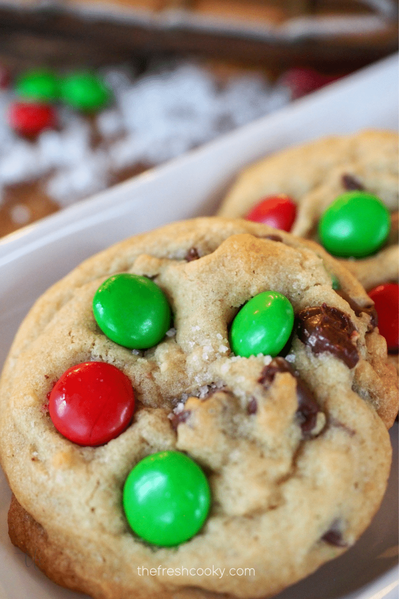 Christmas m & m chocolate chip cookies on tray with fake snow behind, red and green m & m's and sea salt.