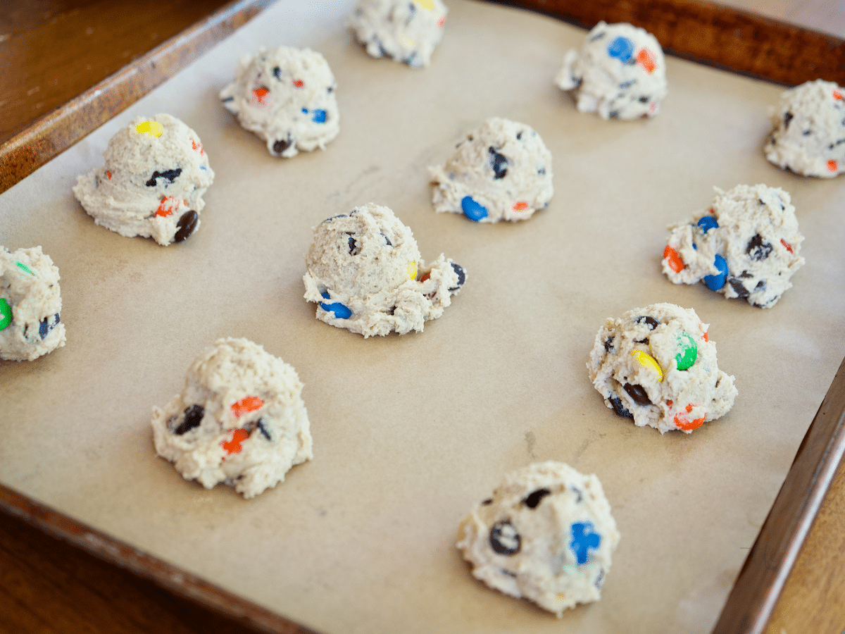 m & m chocolate chip cookie dough balls scooped onto prepared baking sheet, 12 on the sheet.