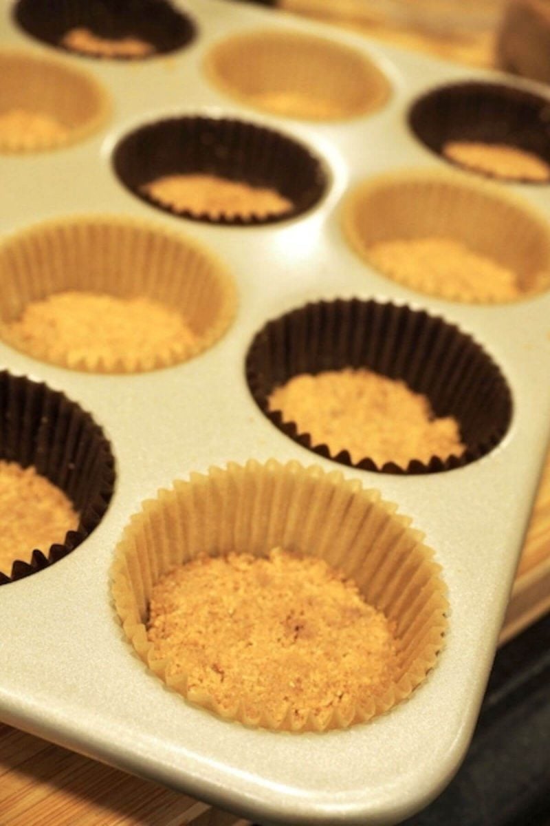 Graham cracker crust mixture pressed into lined muffin tins. 