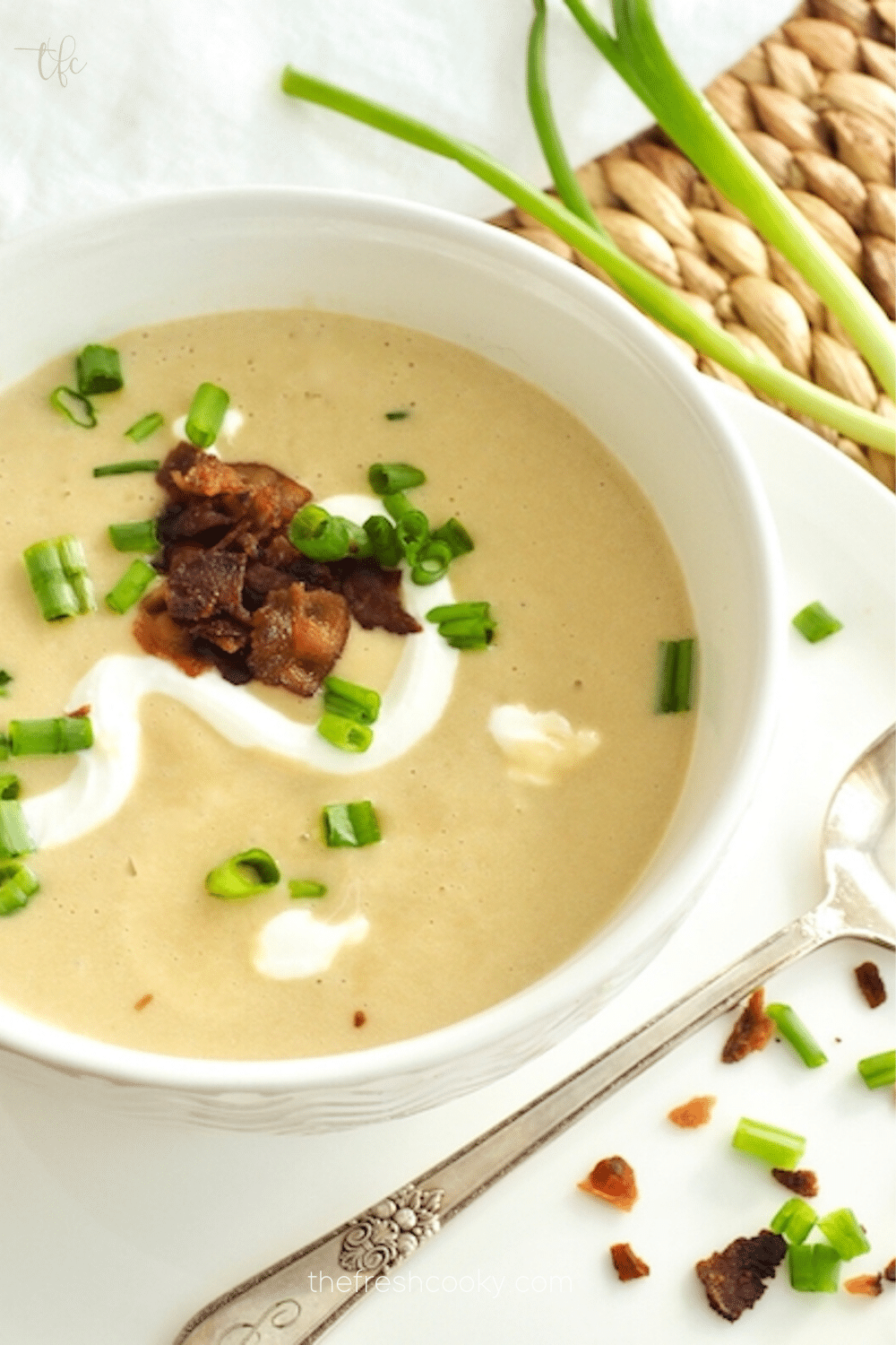 Pin for instant pot potato leek soup with spoon and green onions topped with bacon bits, sour cream and green onions. 