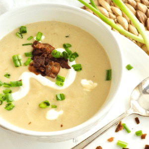 Instant Pot Potato Leek Soup in a white bowl topped with bacon, sour cream and green onions.