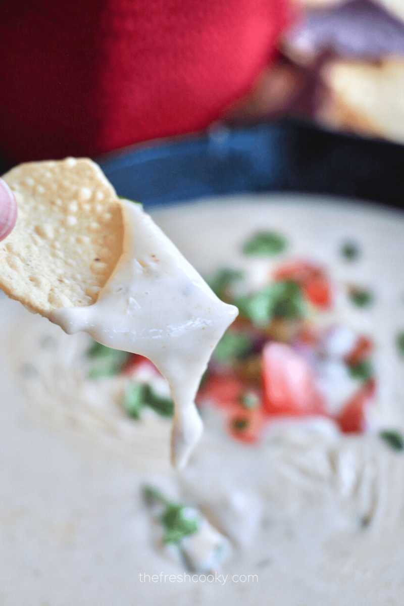 Hand dipping chip into Mexican White Cheese Dip.