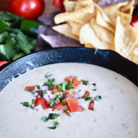 Mexican White Cheese dip square image with fresh toppings and tortilla chips in background.