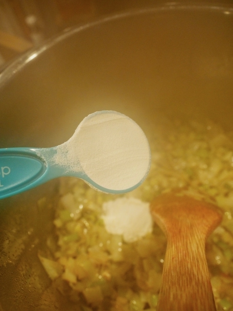 Turquoise tablespoon of flour going into instant pot with ingredients for leek soup.