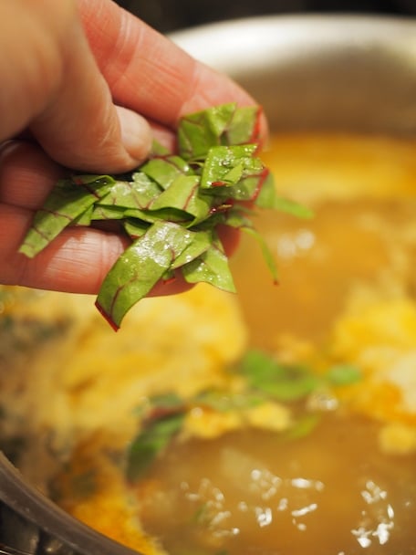 Handful of swiss chard going into soup. Zuppa Toscana Soup | www.thefreshcooky.com